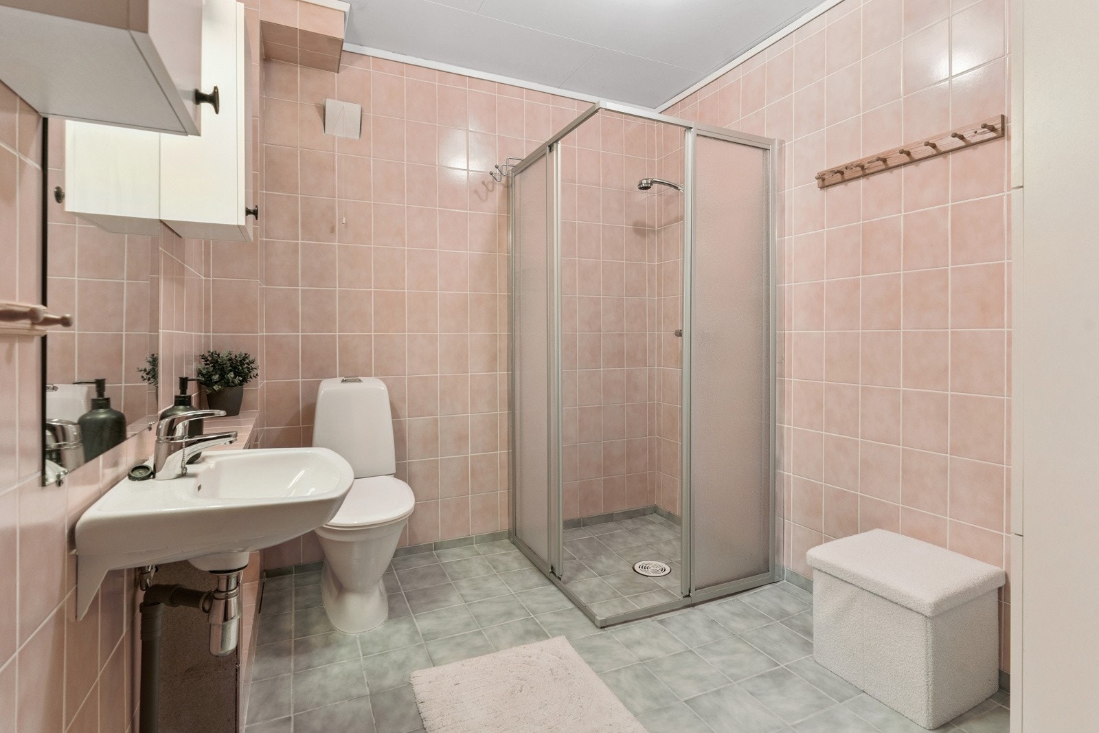 Enkelt flislagt bad med dusjhjørne, servant og WC Galleribilde