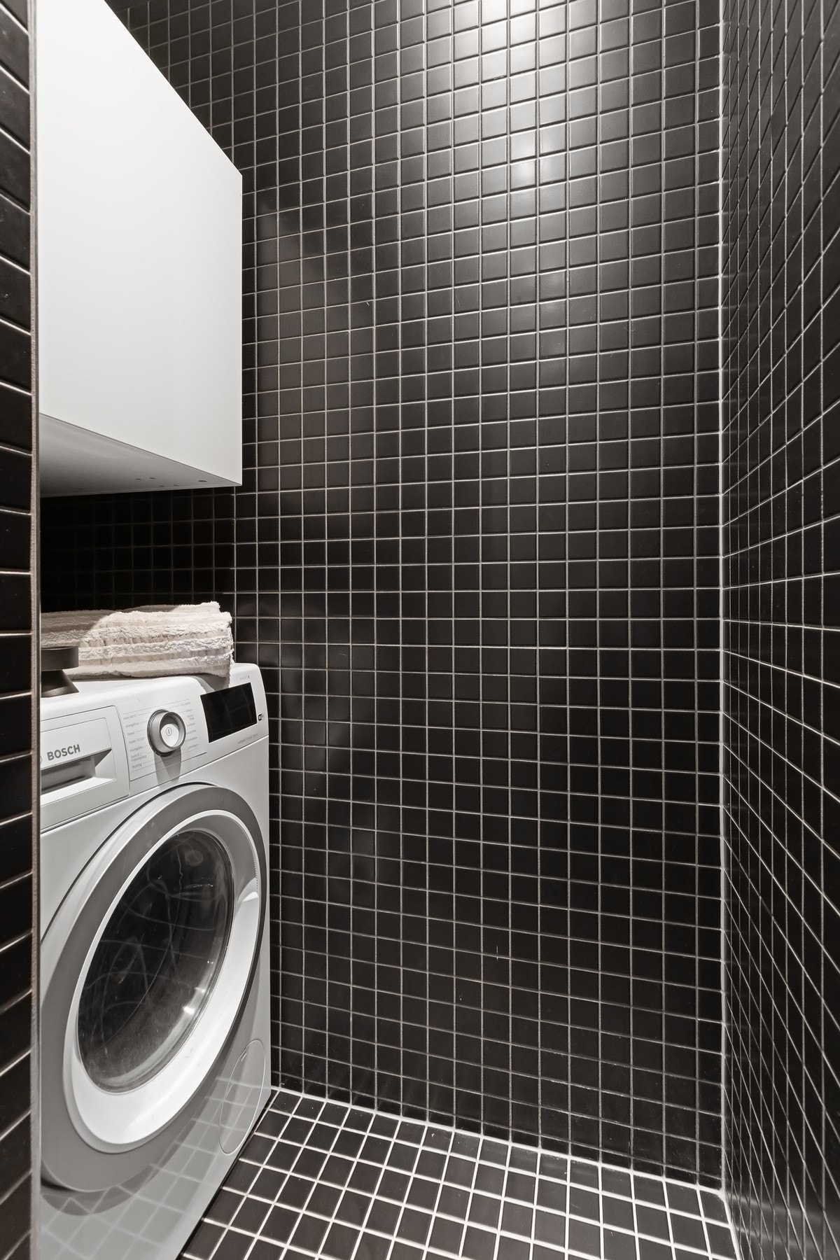 Praktisk nisje på badet med opplegg for vaskemaskin og skap for oppbevaring. Galleribilde