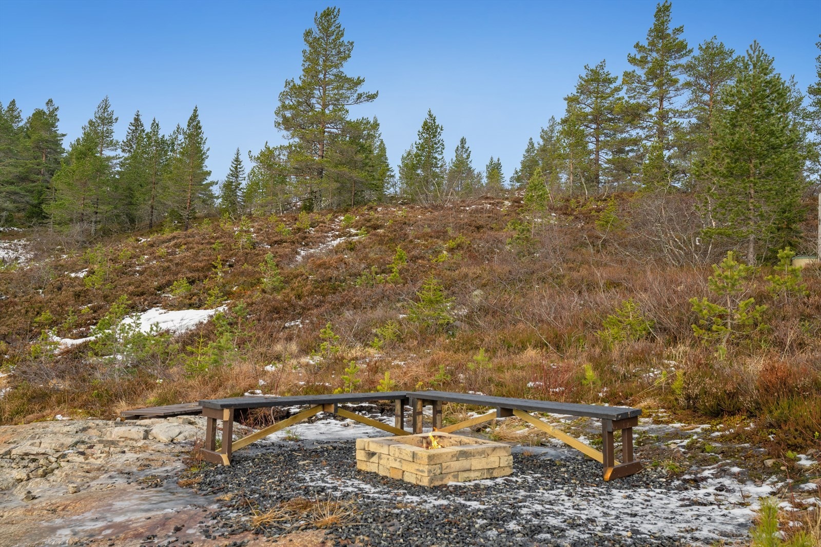 Bålplass med sittebenker er plassert i et naturlig fjellområde, ideelt for utendørs samlinger. Galleribilde