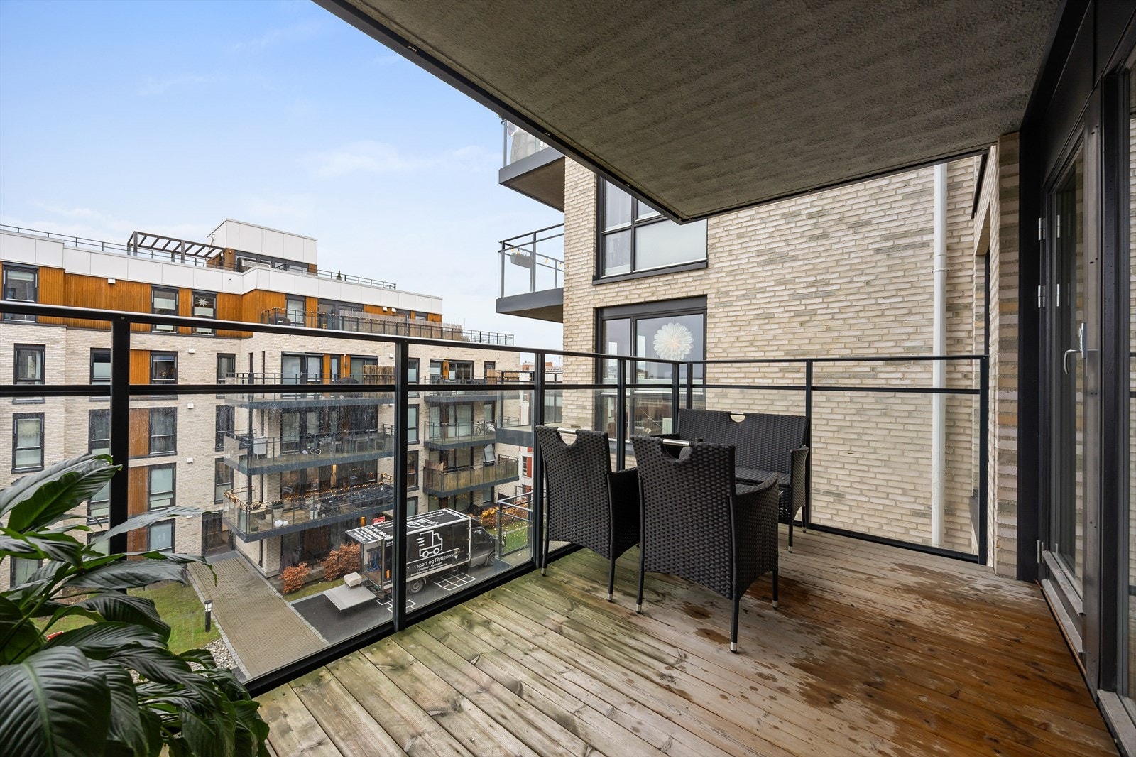 Balkongen har betongdekke belagt med terrassebord og rekkverk i metall med glassfelt. Galleribilde