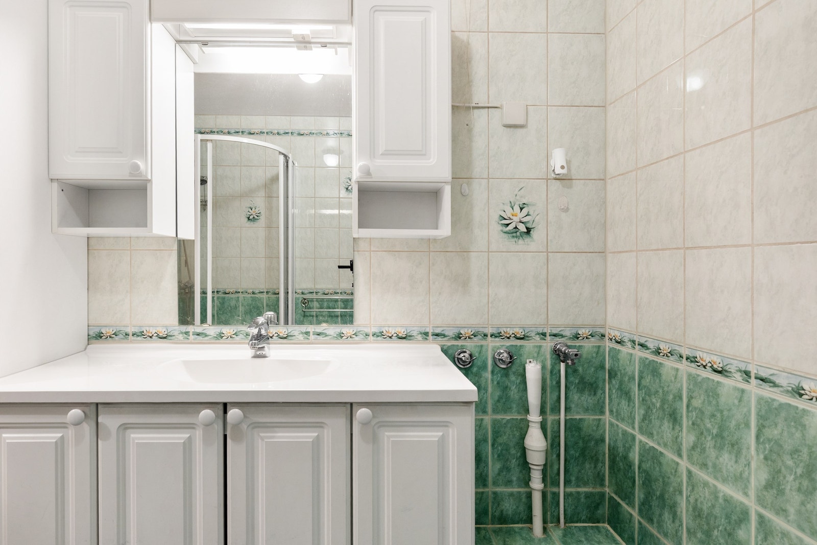 Badet er flislagt på gulv og vegger med elektrisk gulvvarme. Badet er innredet med servant nedfelt i innredning og dusjhjørne med skyvedører. Galleribilde