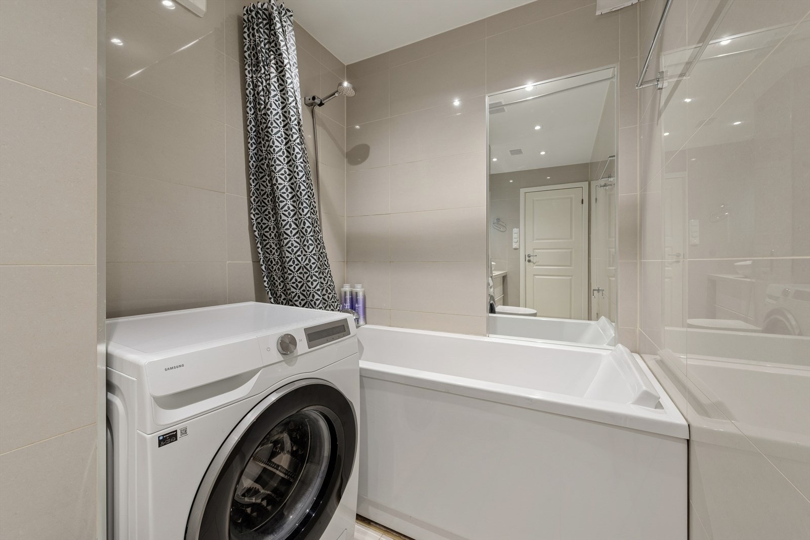 Baderommet er utstyrt med vegghengt toalett, badekar med dusjløsning og opplegg for vaskemaskin Galleribilde