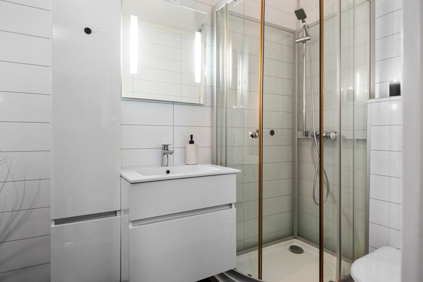 Bad på 4 m² med opplegg til vaskemaskin, toalett, dusjkabinett, servant og oppbevaringsmøblement. Galleribilde