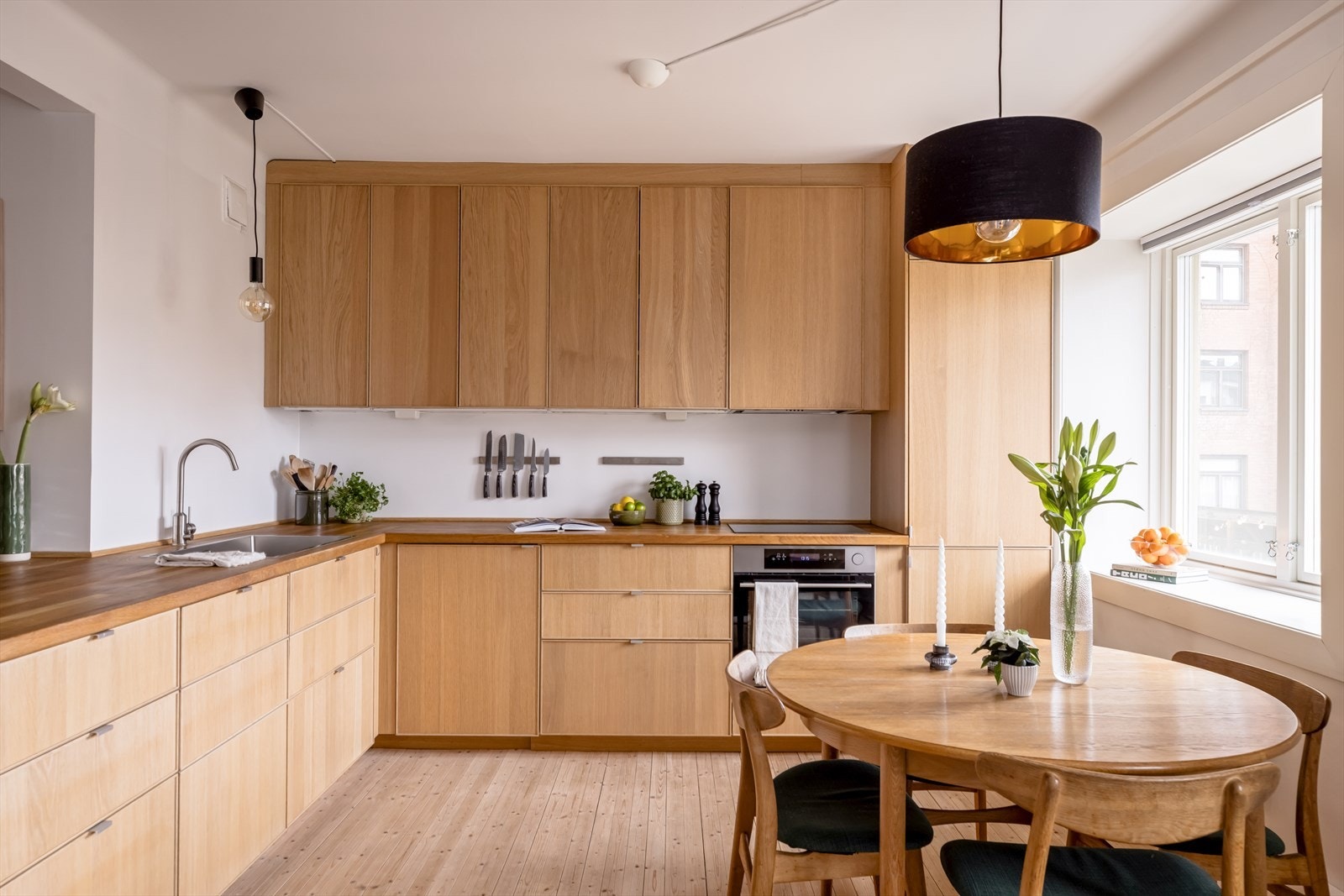 Kjøkkeninnredning med finérte fronter, benkeplate i tre og oppvaskkum i stål. Galleribilde