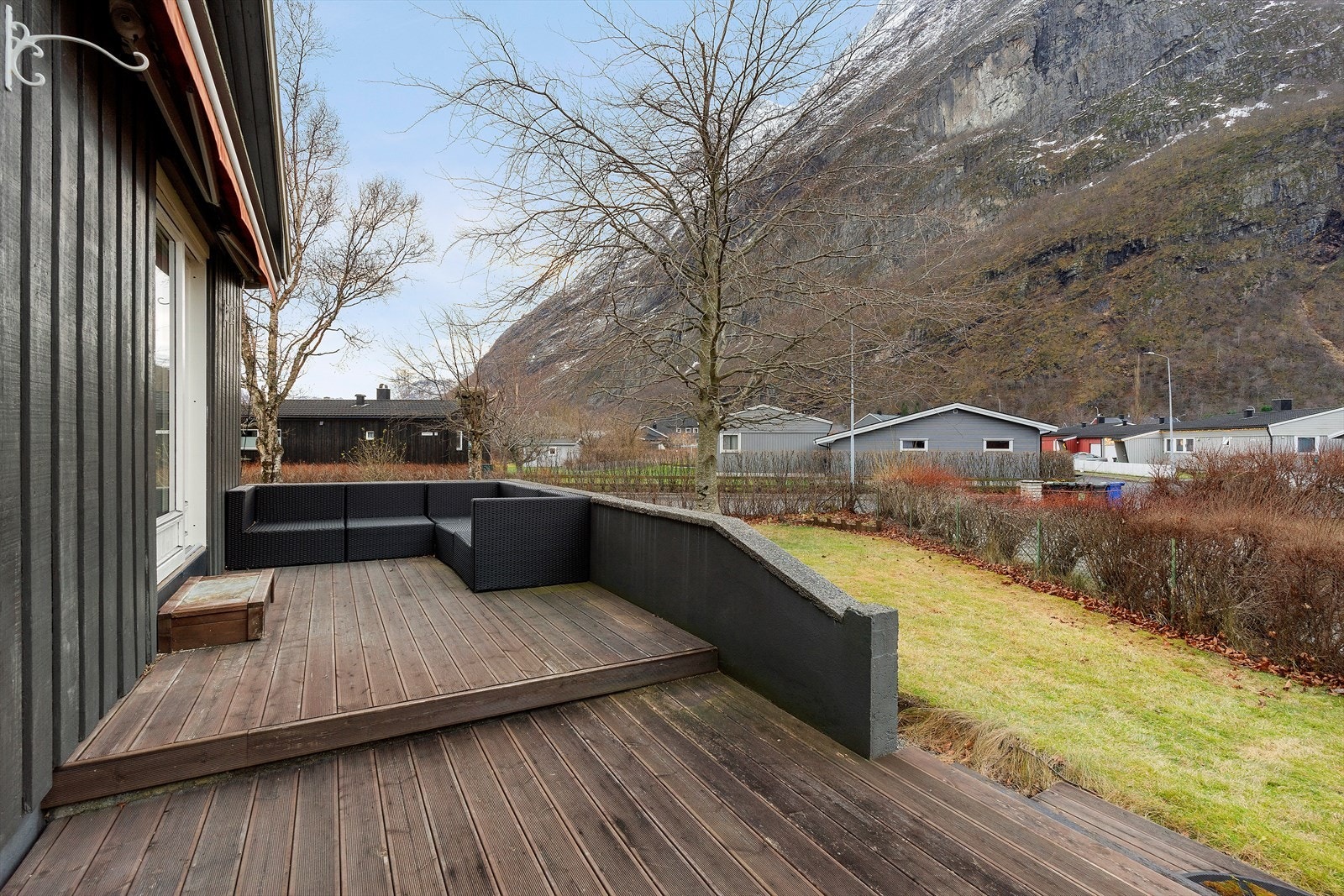 Terrassen er sørvestvendt, har direkte utgang fra stuen og gir utsikt mot fjellandskap. Det er god plass til utemøbler på den romslige treplattingen. Galleribilde