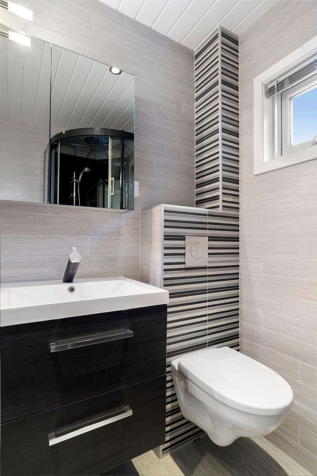 Det er valgt et stilren og moderne design på fliser og baderomsinnredning. Galleribilde