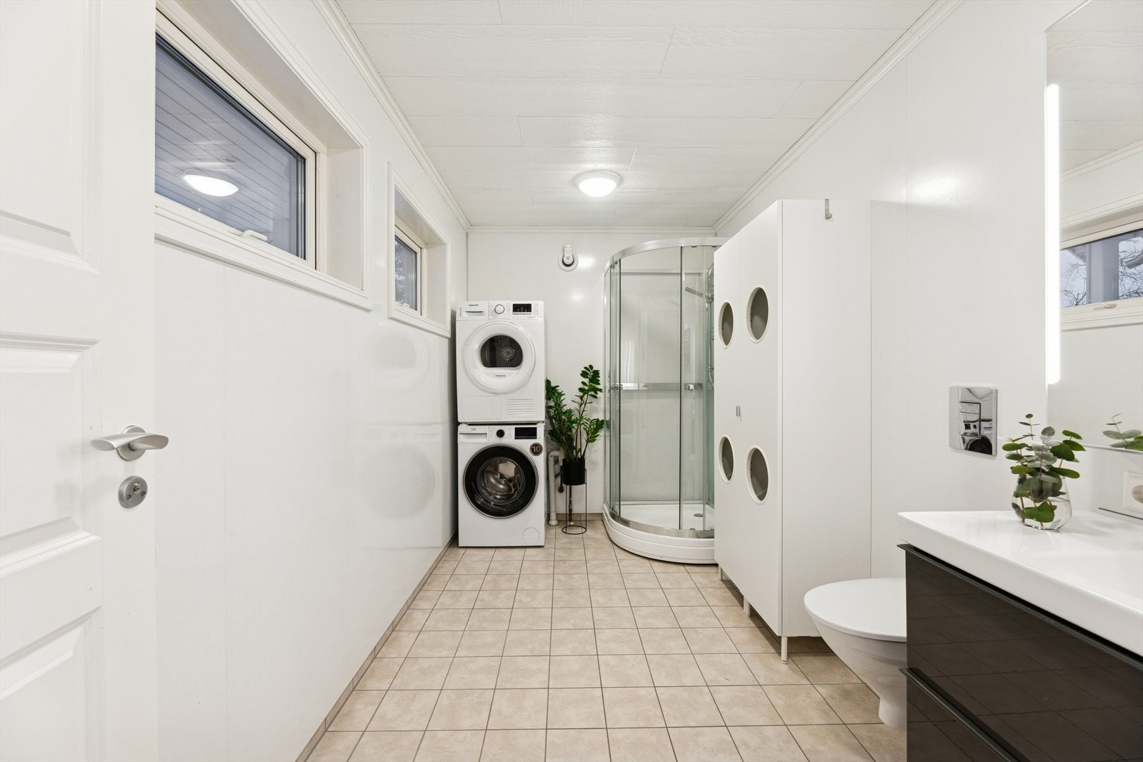 Badet i 1. etasje er et kombinert bad/vaskerom med flislagt gulv og varmekabler. Veggene er kledd med våtromsplater, og i himlingen er det himlingsplater. Galleribilde