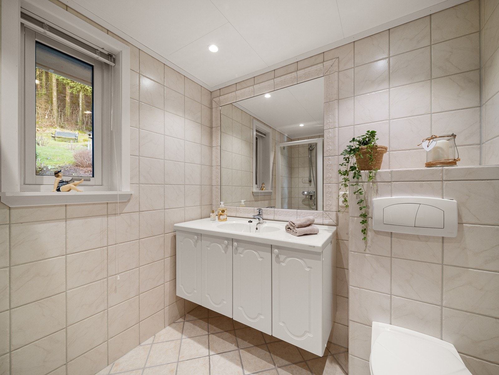 Badet er av god størrelse og har dusjdør, servant, baderomsmøbel og vegghengt WC Galleribilde