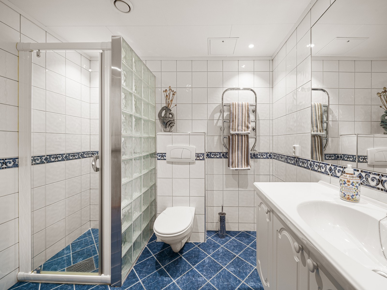 Bad med dusjdør, servant, baderomsmøbel og vegghengt wc samt gulvvarme Galleribilde