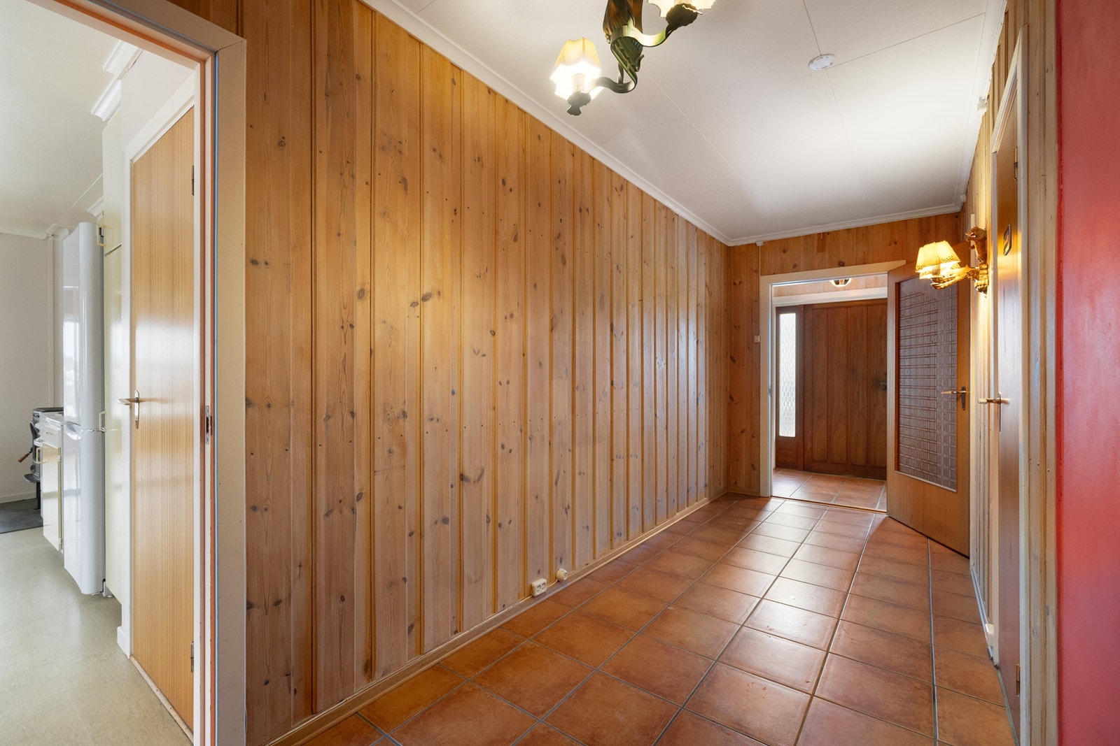 Romslig entré og hall med flislagt gulv og trepanel. Galleribilde