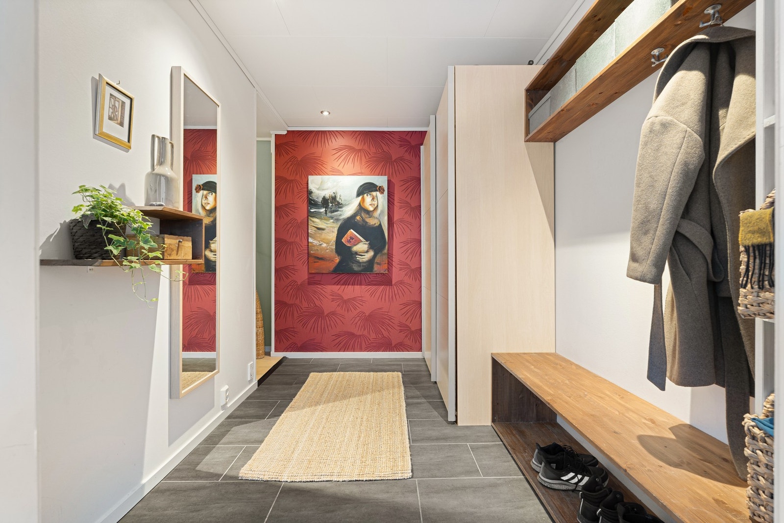 Halvplan ned fra kjøkkenet ligger en romslig og moderne entré med rikelig oppbevaringsplass. Galleribilde