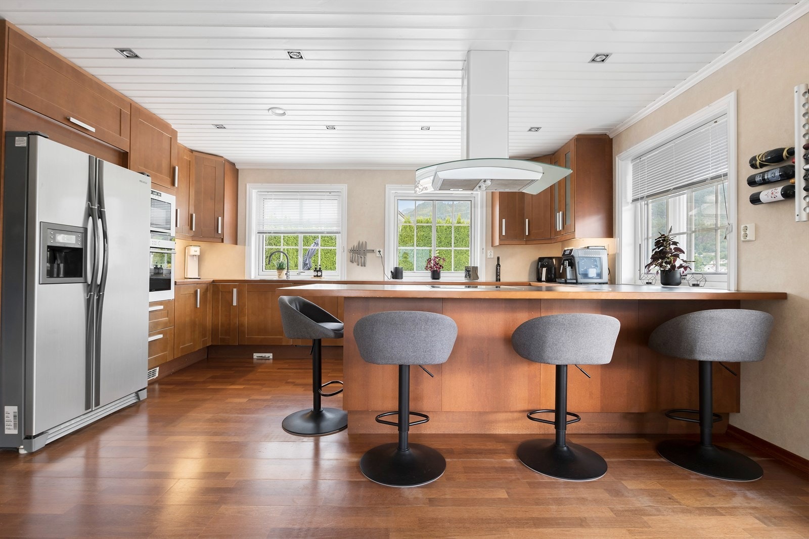 Flott, stort kjøkken med fronter i kirsebær. Kjøkkenøy med spiseplasser og platetopp Galleribilde