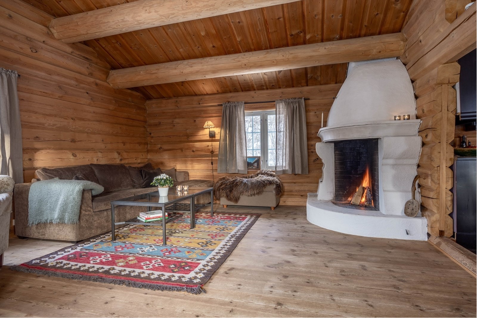 Stemningsfull stue med peis og solide tømmerkonstruksjoner. Galleribilde