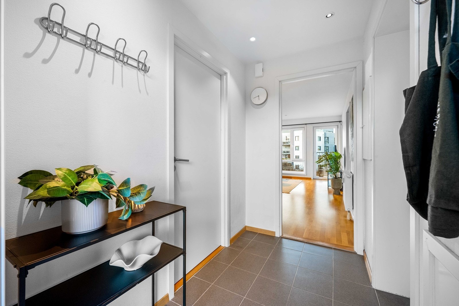 Entré med grå fliser ved inngangen og parkett videre innover i leiligheten. Galleribilde