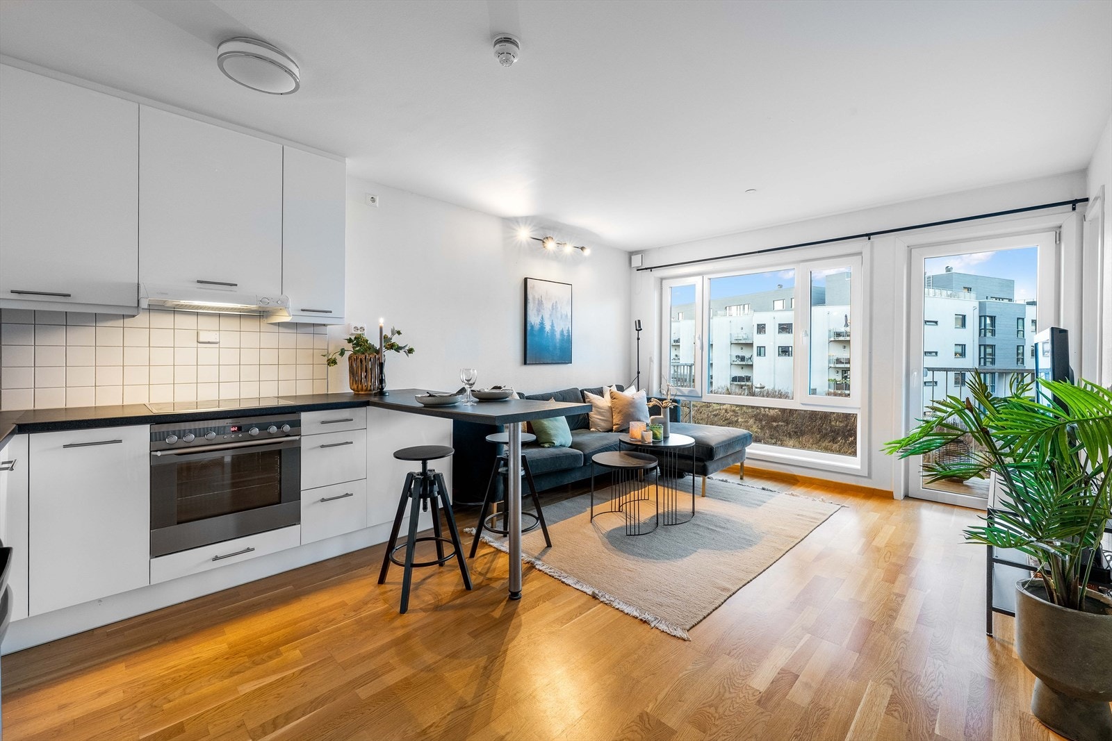 Kjøkkeninnredning har glatte fronter, laminert benkeplate og fliser på vegg over benkeplaten. Galleribilde