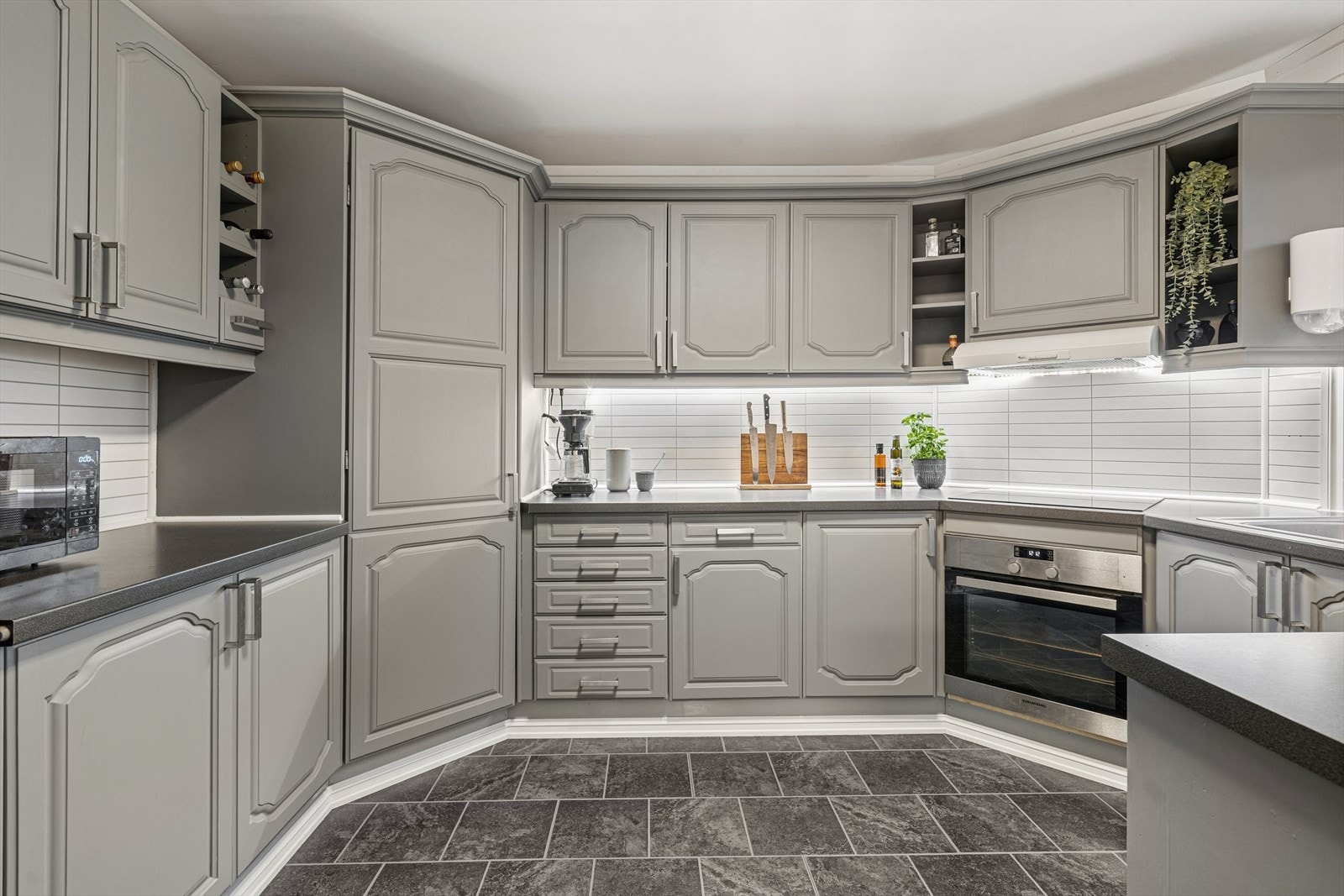 Innredningen er tidløs med gråmalte profilerte fronter og benkeplate i laminat Galleribilde