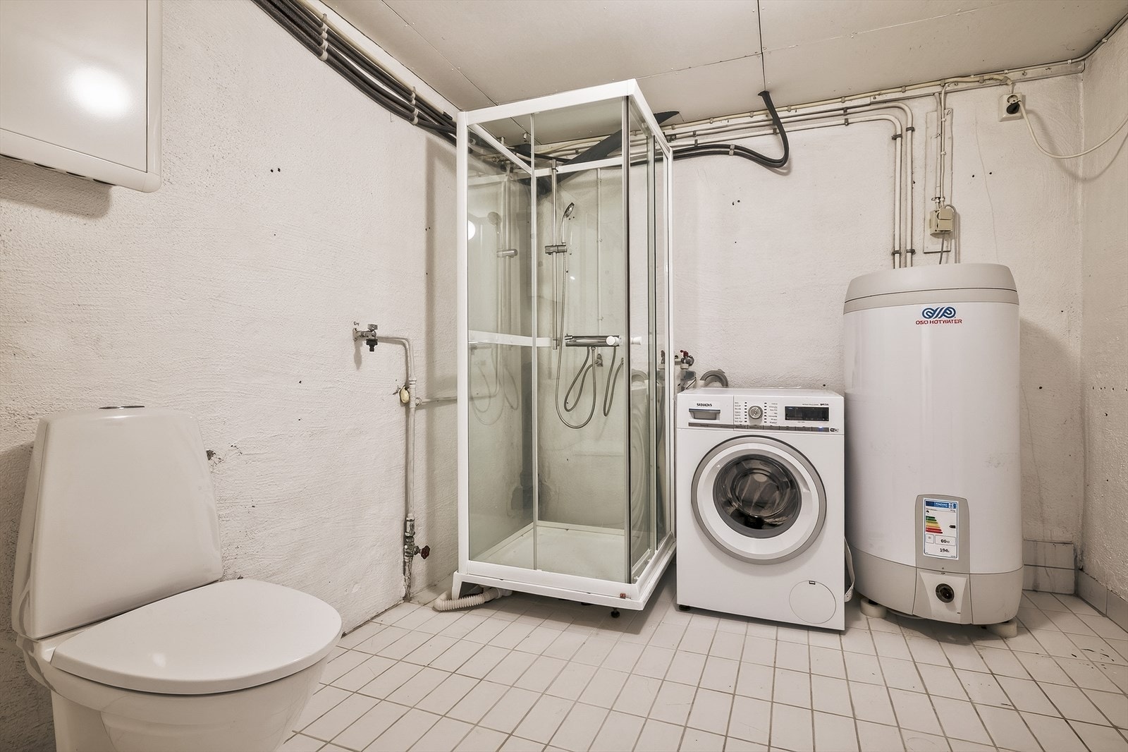Romslig vaskerom med dusjkabinett, toalett, vaskemaskin og varmtvannsbereder. Praktisk løsning for en funksjonell hverdag Galleribilde