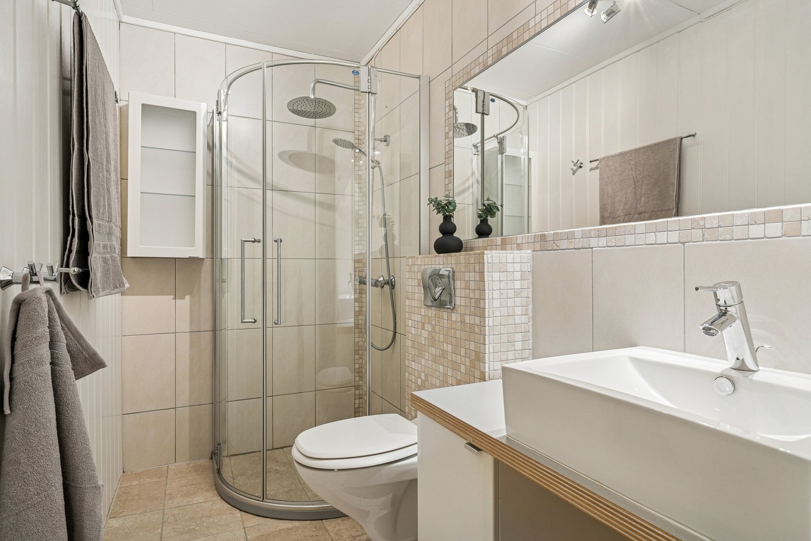 Flislagt bad i underetasje med varmekabler i gulv. Badet er innredet med servant, dusjkabinett og vegghengt WC. Galleribilde