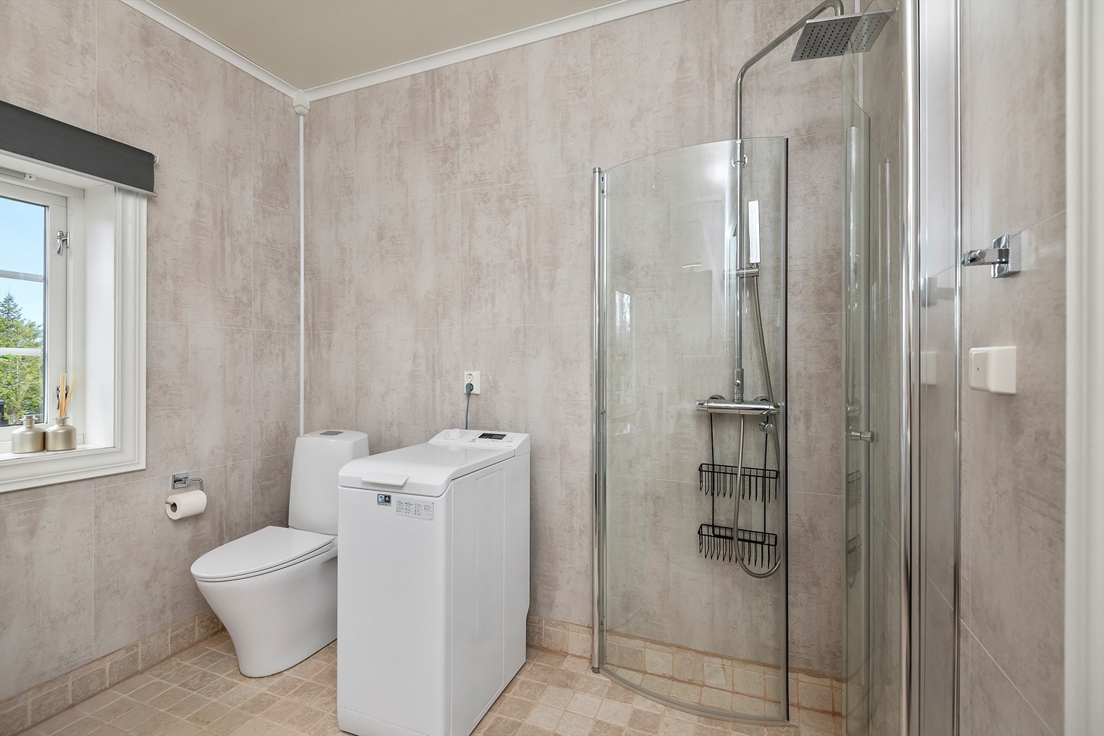Gulvmontert WC, dusj med innfellbare glassdører og opplegg for vaskemaskin. Fint lys inn gjennom vinduet. Galleribilde