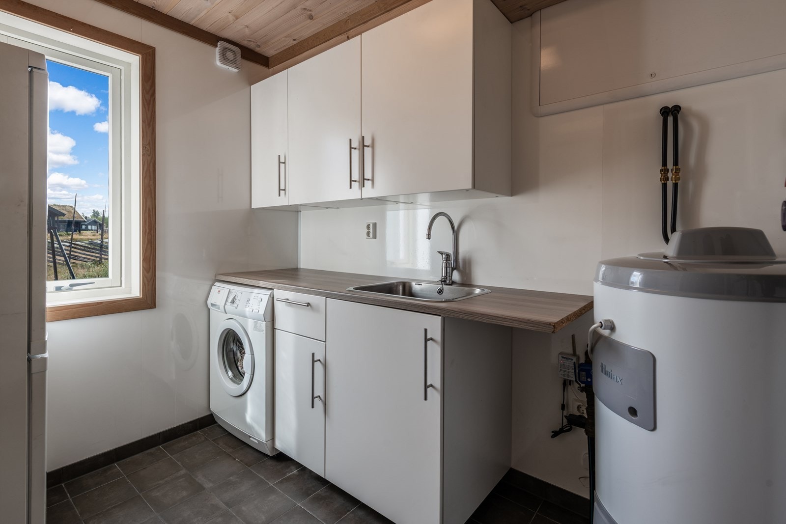 Veldig praktisk vaskerom med innredning, vask og opplegg for vaskemaskin. Galleribilde