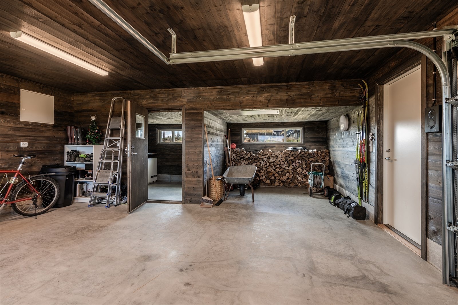 Svært gjennomført garasje med vegger og tak kledd i panel. Det er montert elbil lader. Galleribilde