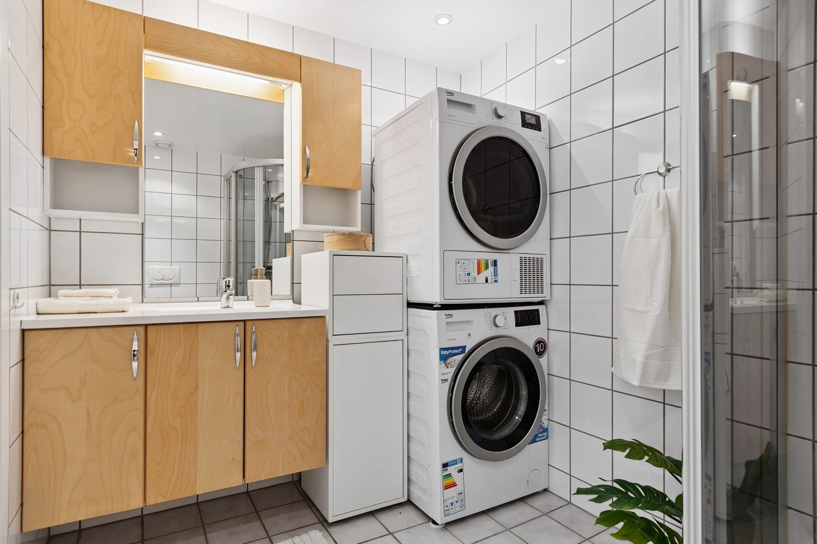 Flislagt bad utstyrt med servantskap, opplegg for vaskemaskin, veggmontert wc, dusjkabinett og mekanisk avtrekk. Galleribilde