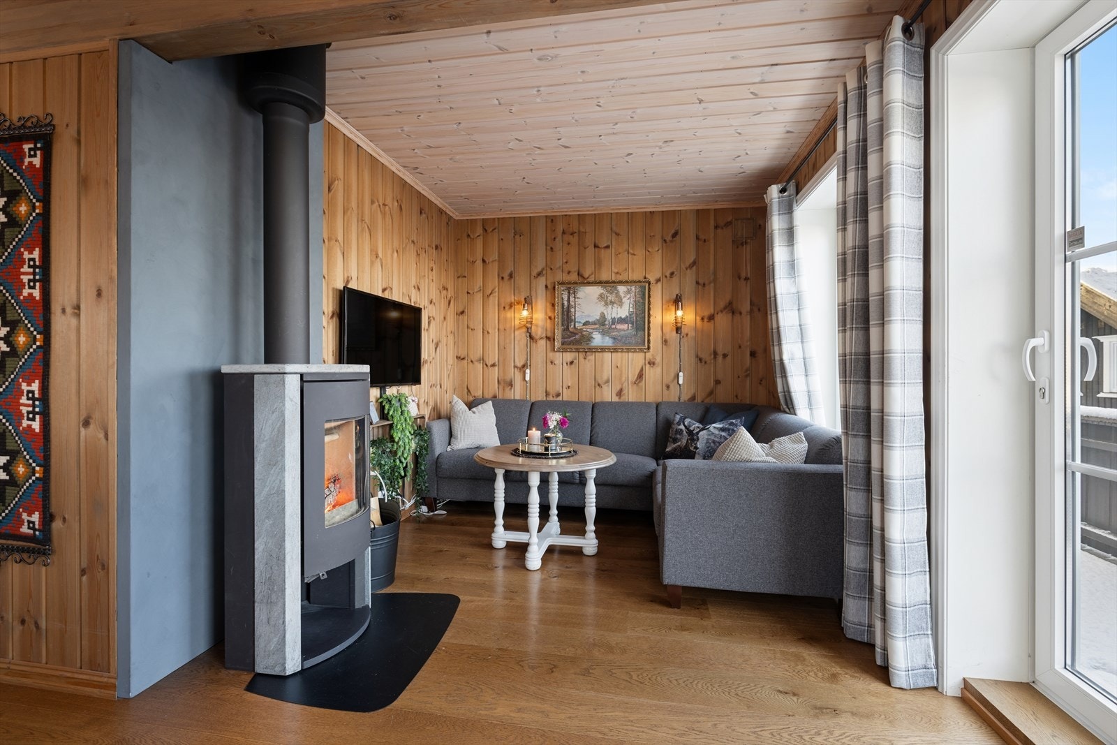 Lun og koselig stue med vedovn som gir både varme og stemning! Den åpne løsningen og store vindusflater gir godt lysinnslipp og en herlig utsikt, mens sofakroken innbyr til avslapning etter en dag ute i naturen. Perfekt for hyggelige kvelder foran peisen. Galleribilde