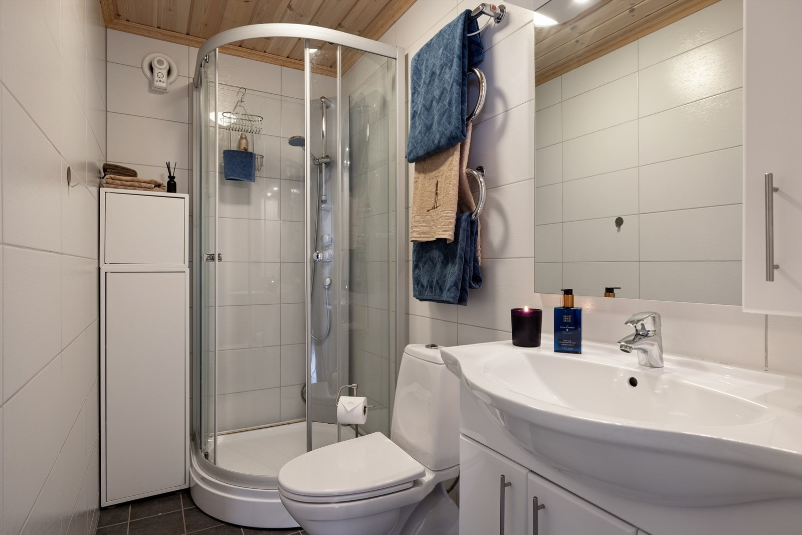 Praktisk baderom med dusjkabinett, stilrene fliser og god oppbevaringsplass. Her får du en funksjonell løsning med lyse overflater og varme detaljer Galleribilde