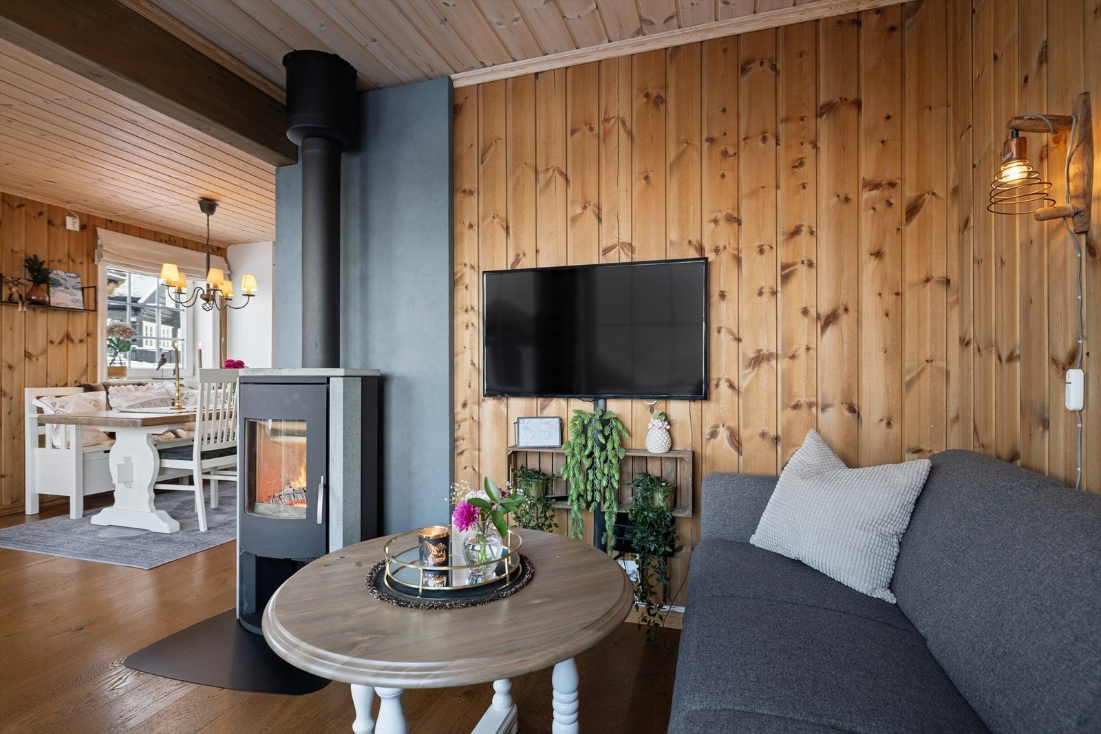 Lun og koselig stuekrok med vedovn som gir både varme og stemning. Her kan du slappe av foran peisen etter en dag ute, med TV og komfortabel sitteplass i en klassisk hytteatmosfære. Den åpne løsningen mot spiseplassen gjør rommet sosialt og innbydende. Galleribilde