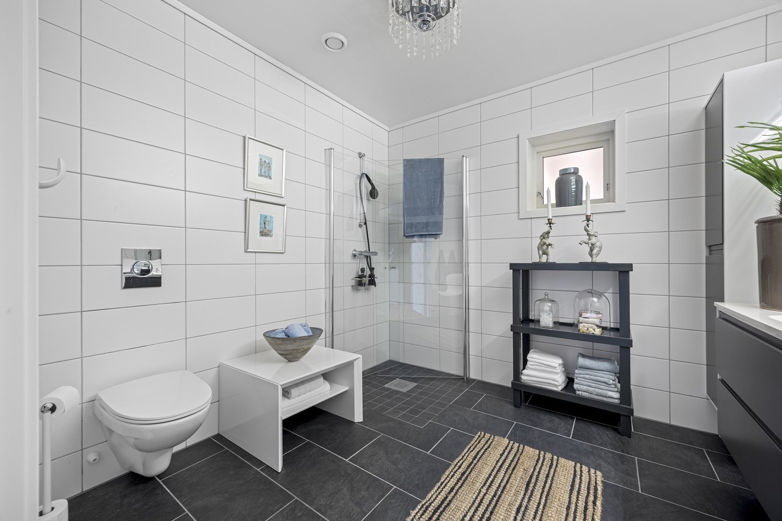 Hovedbad med fliser til tak, dusjhjørne, vegghengt toalett og servantinnredning med underskap. Galleribilde