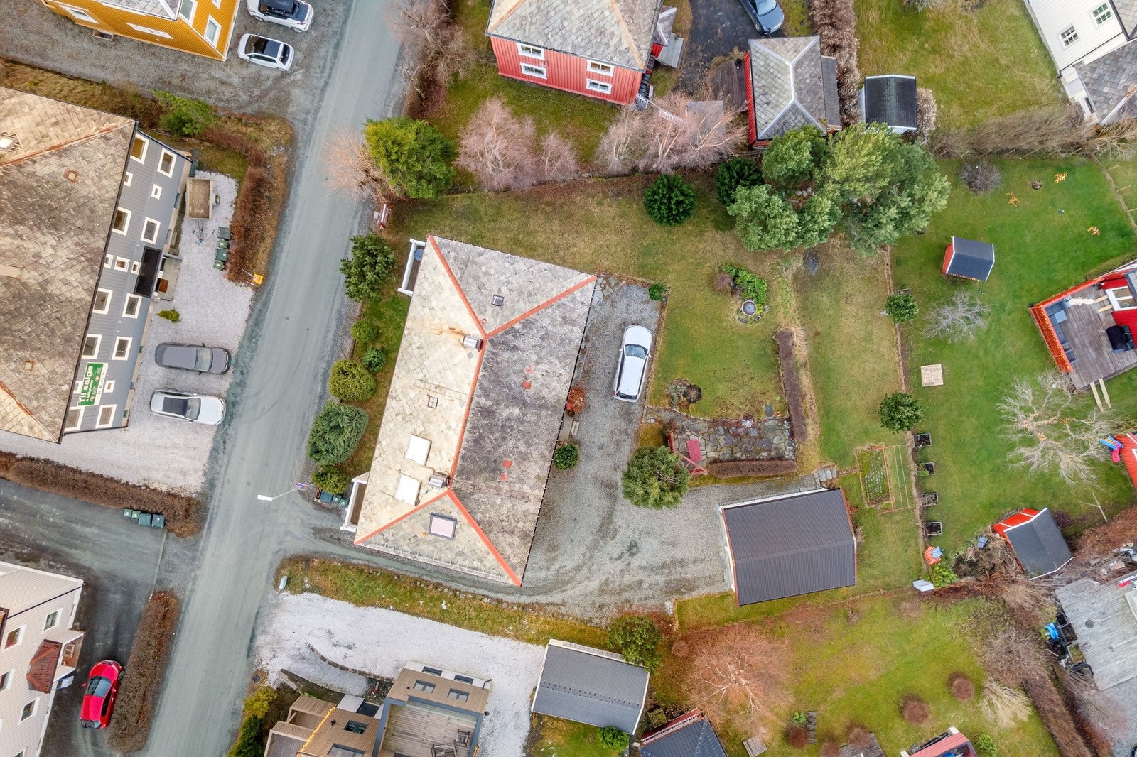 Oversiktsbilde av eiendommen. Tomten er relativt flat, men i hagen har man to "nivåer", der en hekk og annen beplantning skiller de to ulike nivåene. Galleribilde