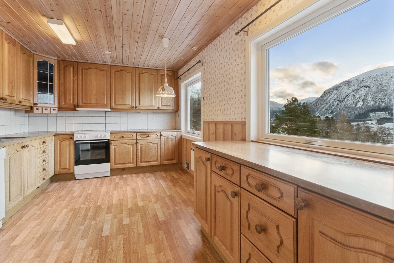 Romsleg kjøkken med særs god skap-, skuffe og benkeplass. Store vindauge gjev godt arbeidslys og nydeleg utsikt til matlaginga Galleribilde