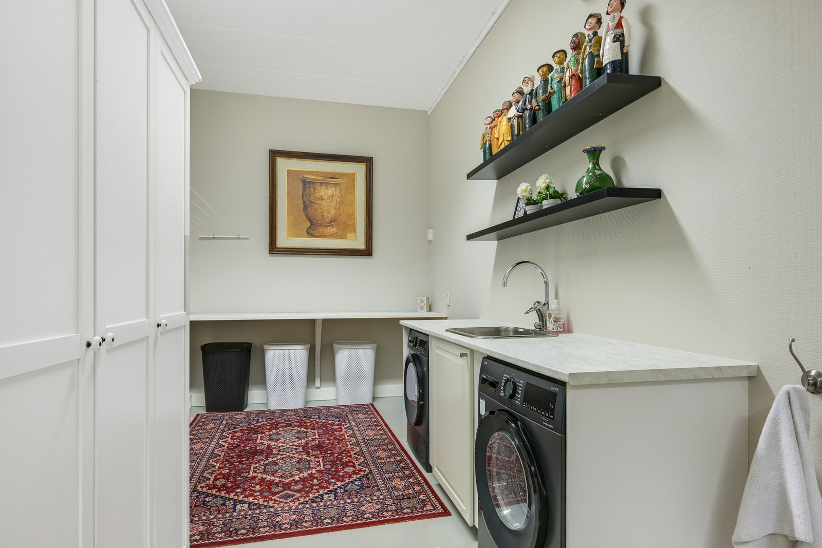 Praktisk vaskerom med praktisk innredning - benkeplater, skap og plassbygget opplegg til vaskemaskin og tørketrommel, samt utslagskom. (Næring/lager) Galleribilde