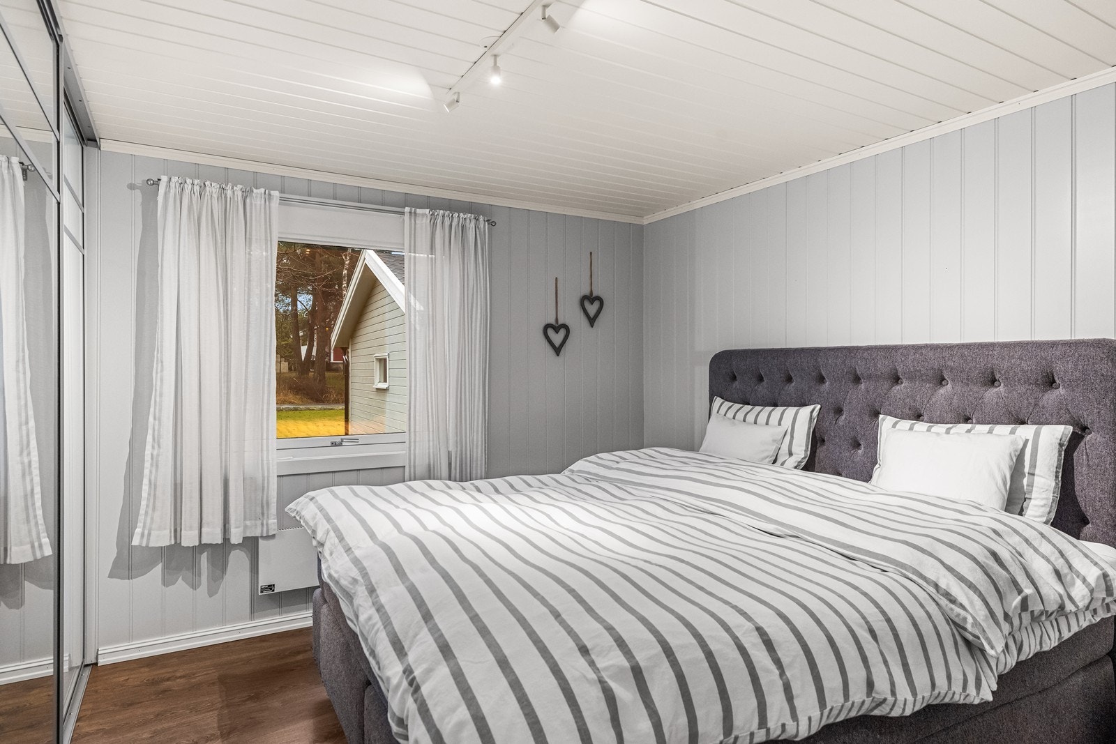 Hovedsoverom med lyse overflater og stor skyvedørsgarderobe med speil Galleribilde