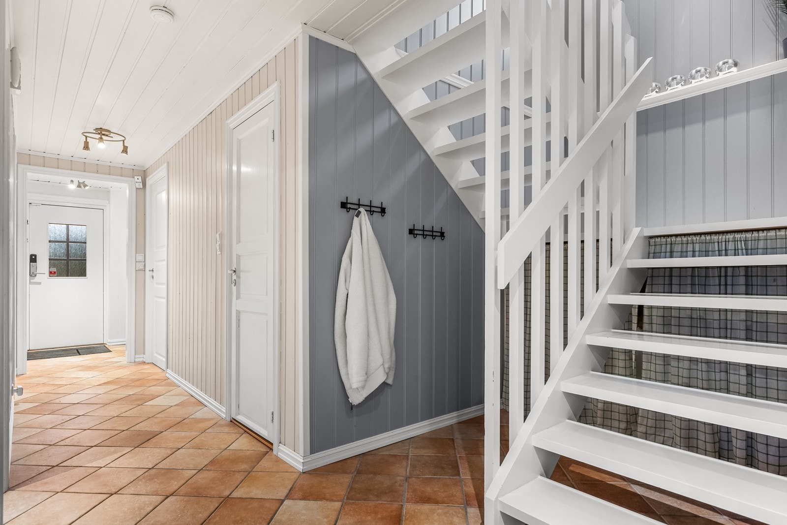 Lys og flislagt entré/mellomgang med underliggende varmekabler og trapp til andre etasje Galleribilde