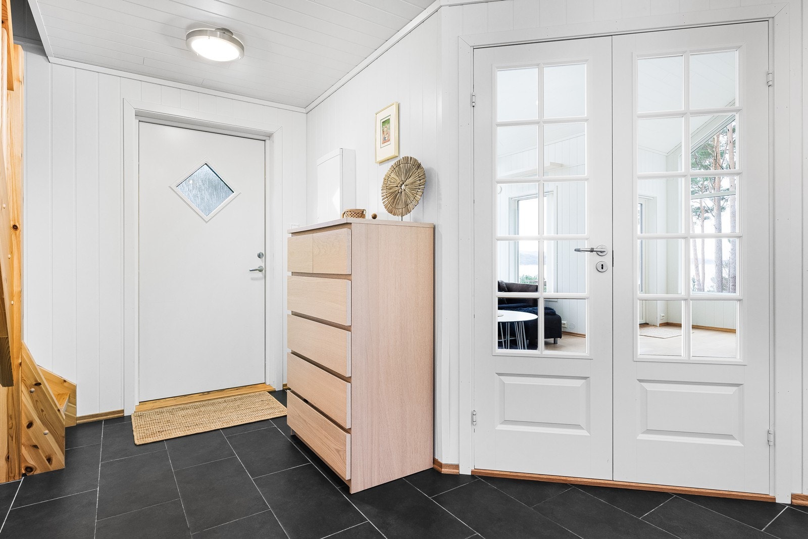 Romslig gang med fliser på gulv. Det er varmekabler i gulver både i gang, bad, stue og kjøkken. Galleribilde