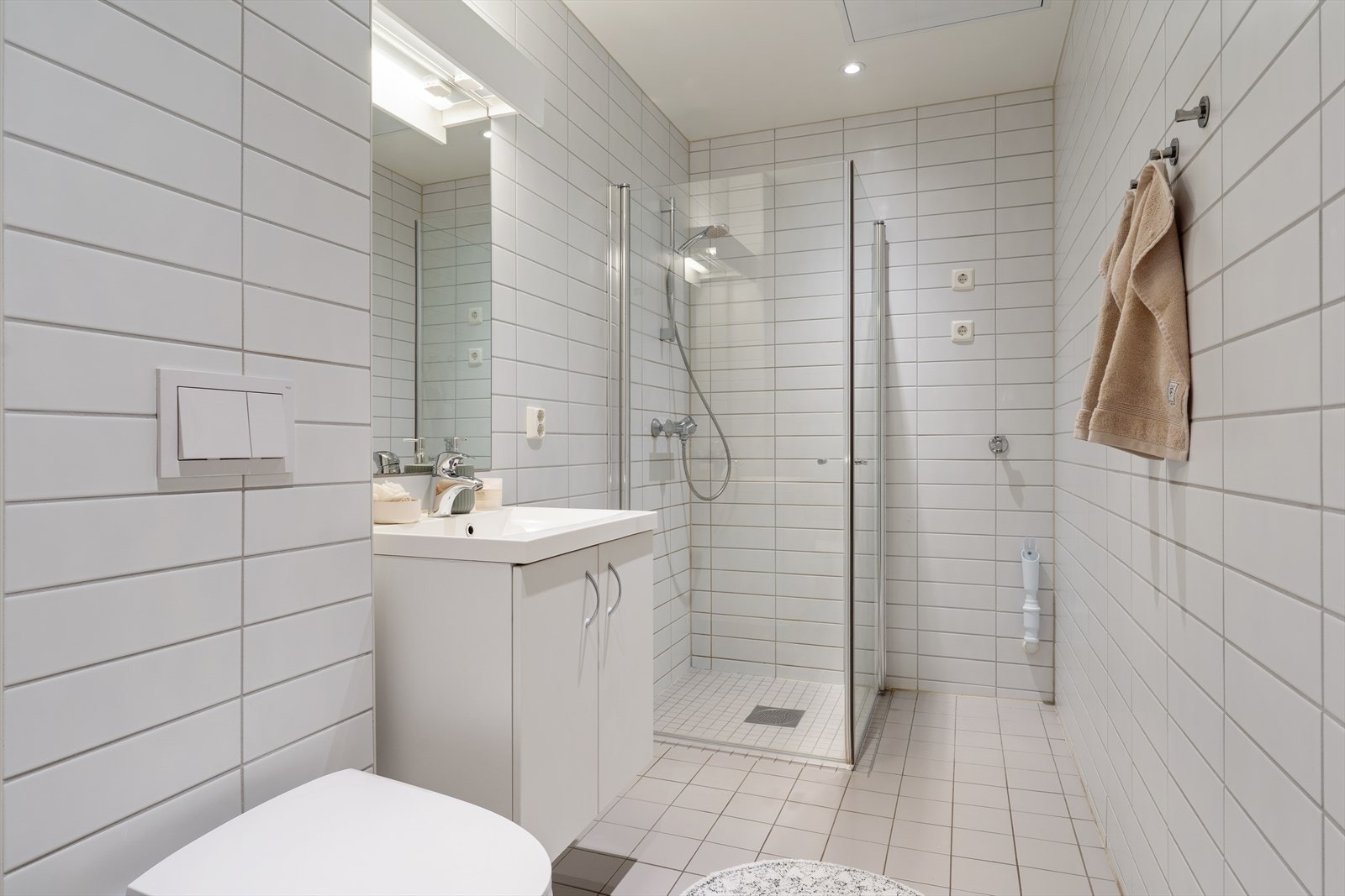 Badet fungerer som et kombinert bad og vaskerom, utført i et tidløst fargevalg. Rommet har flislagte vegger og gulv, samt malt himling. Det er elektriske varmekabler i gulvet for komfort. Galleribilde