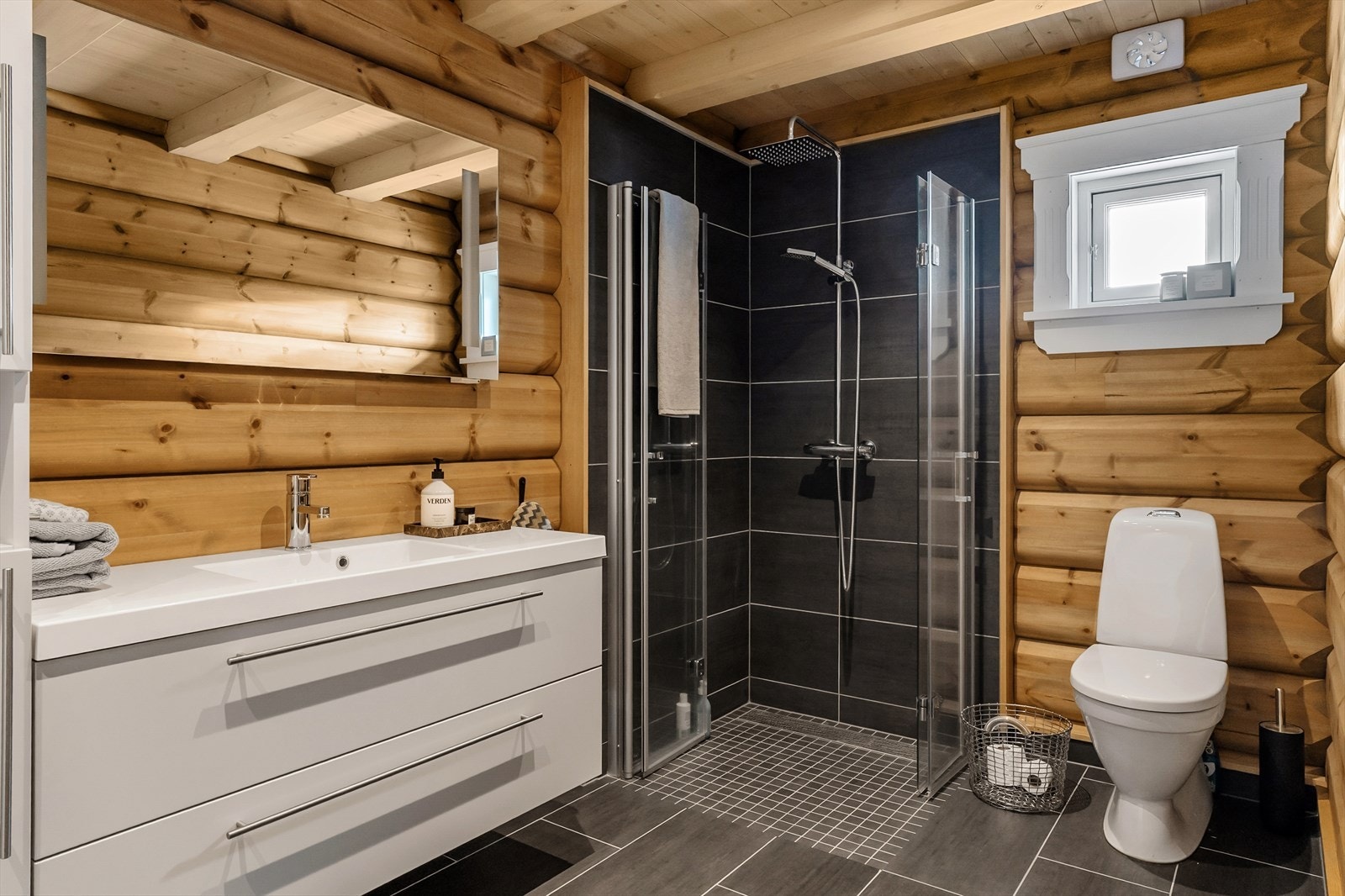 Flott baderom som inneholder servant med skap, toalett og dusjhjørne. Gulvet er flislagt og dusjgulvet er nedsenket med 5 mm. Himling har panel og vegger av tømmer (flislagte vegger i dusjhjørnet). Rommet har elektrisk gulvvarme. Galleribilde
