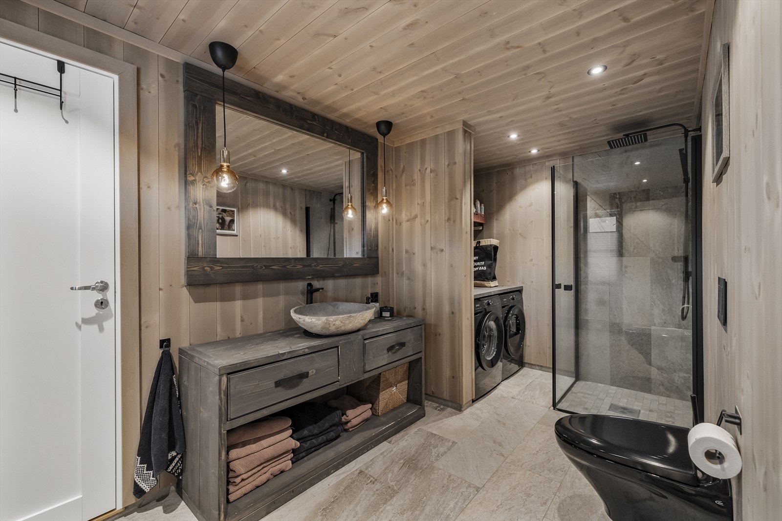 Lekkert hovedbad med servant, veggmontert toalett, dusjhjørne med innfellbare glassvegger og opplegg for vaskemaskin. Elektrisk avtrekksvifte Galleribilde