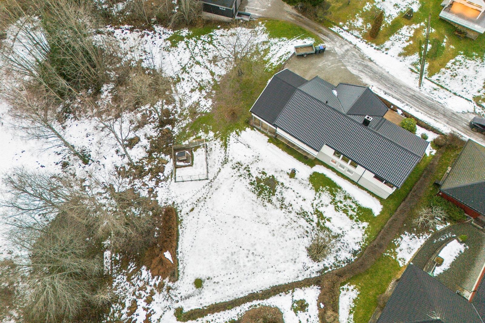 Tomten er pen opparbeidet med plen og beplantning, støttemur og steinlagt gårdsplass. Galleribilde