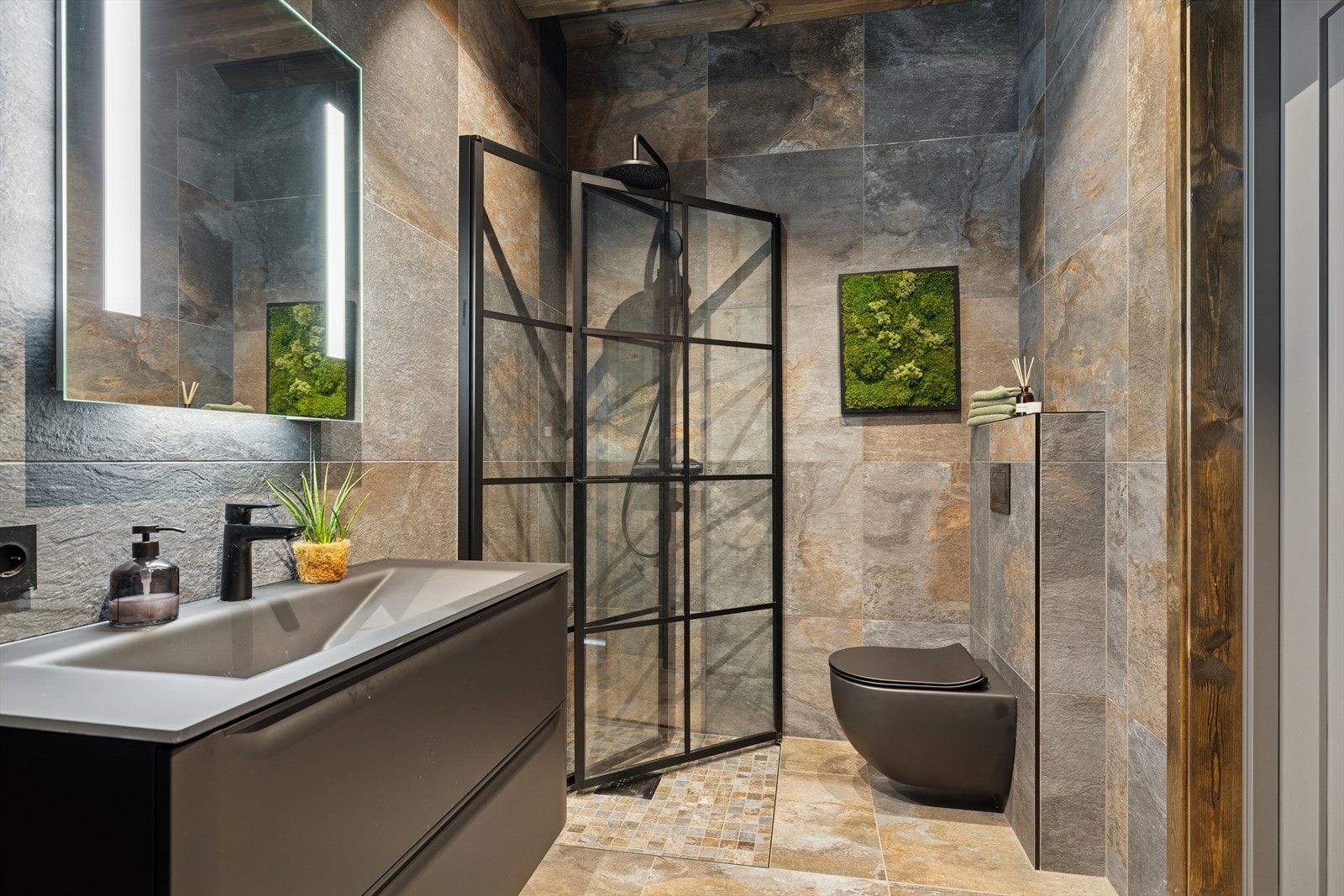 Moderne baderom med fliser, varmekabler, servant, dusj, wc og opplegg for vaskemaskin. Galleribilde