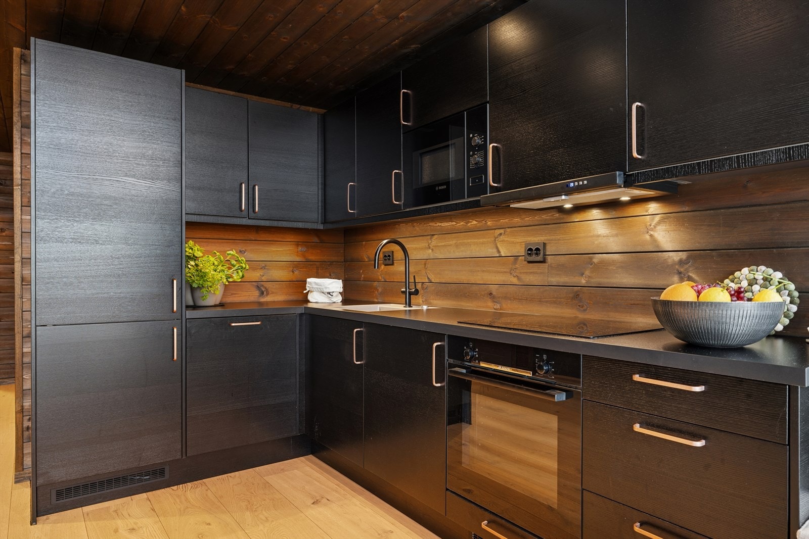 Moderne og funksjonelt kjøkken med integrerte hvitevarer, gode oppbevaringsmuligheter og elegante sorte fronter. Galleribilde