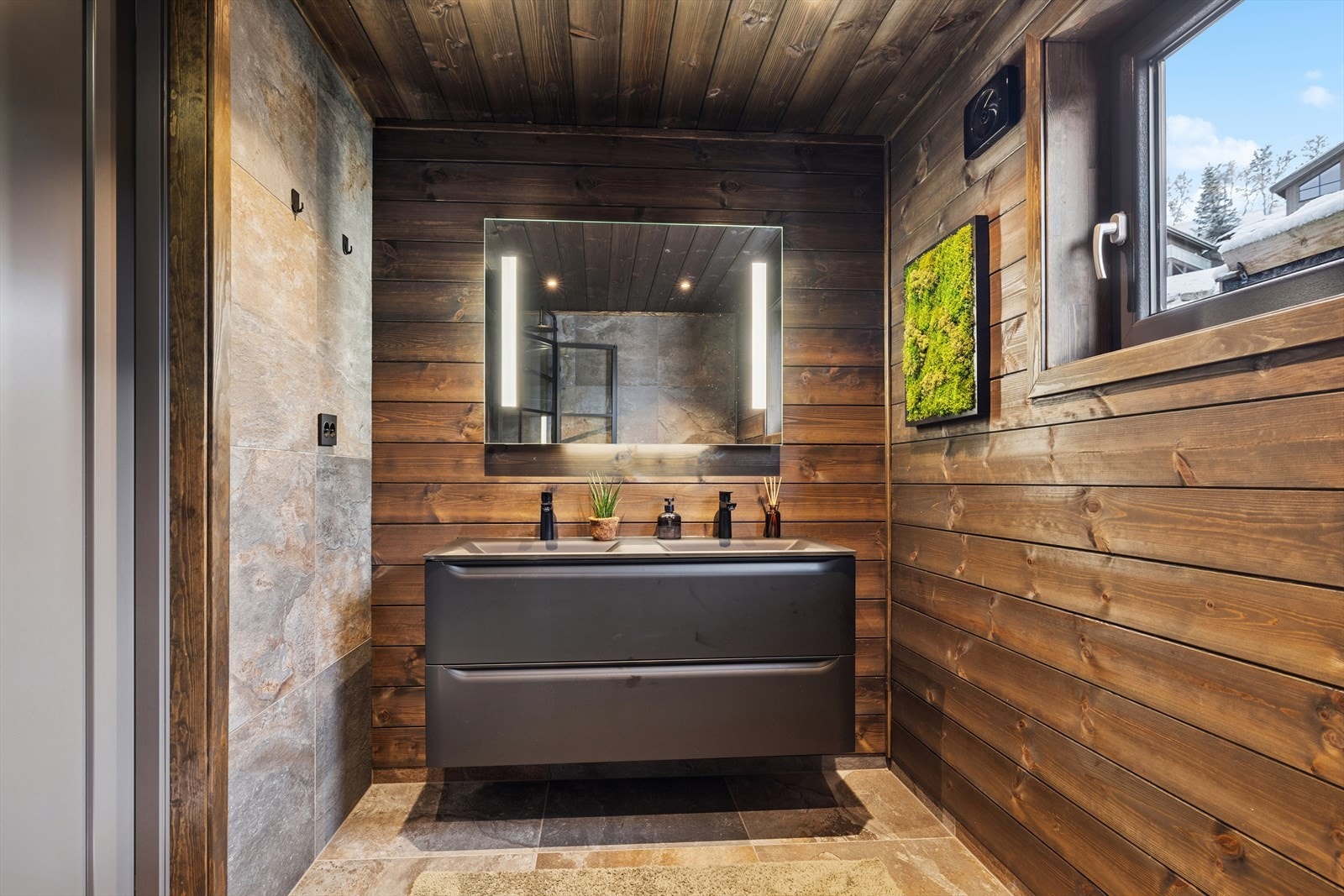 Romslig og moderne baderom med fliser, varmekabler, dobbelservant, dusj og wc. Stilrent og innbydende. Galleribilde