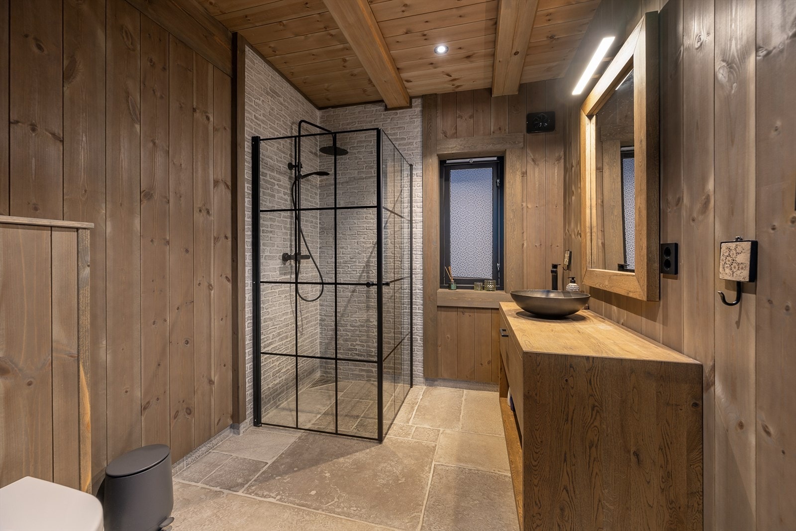 Delikat baderom med steinfliser på gulv og teglsteinsfliser i dusjsonen. Galleribilde