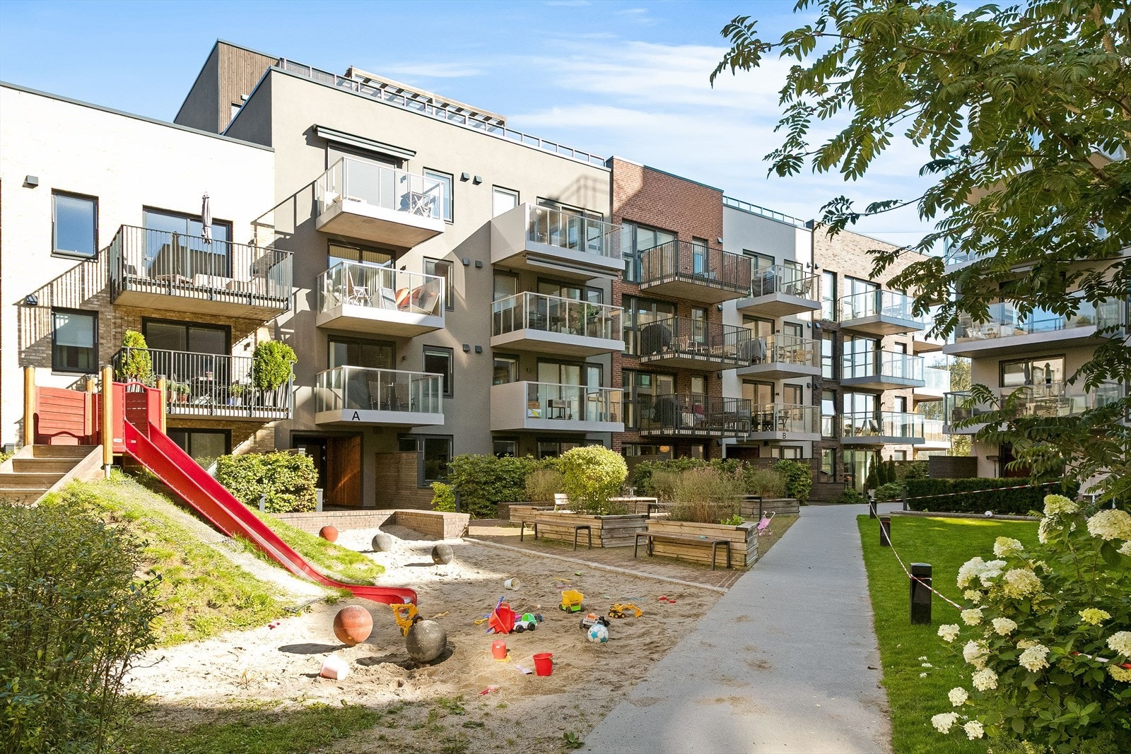 Felles tomt for borettslaget bestående av plenarealer med trær, busker og diverse beplantning. Galleribilde