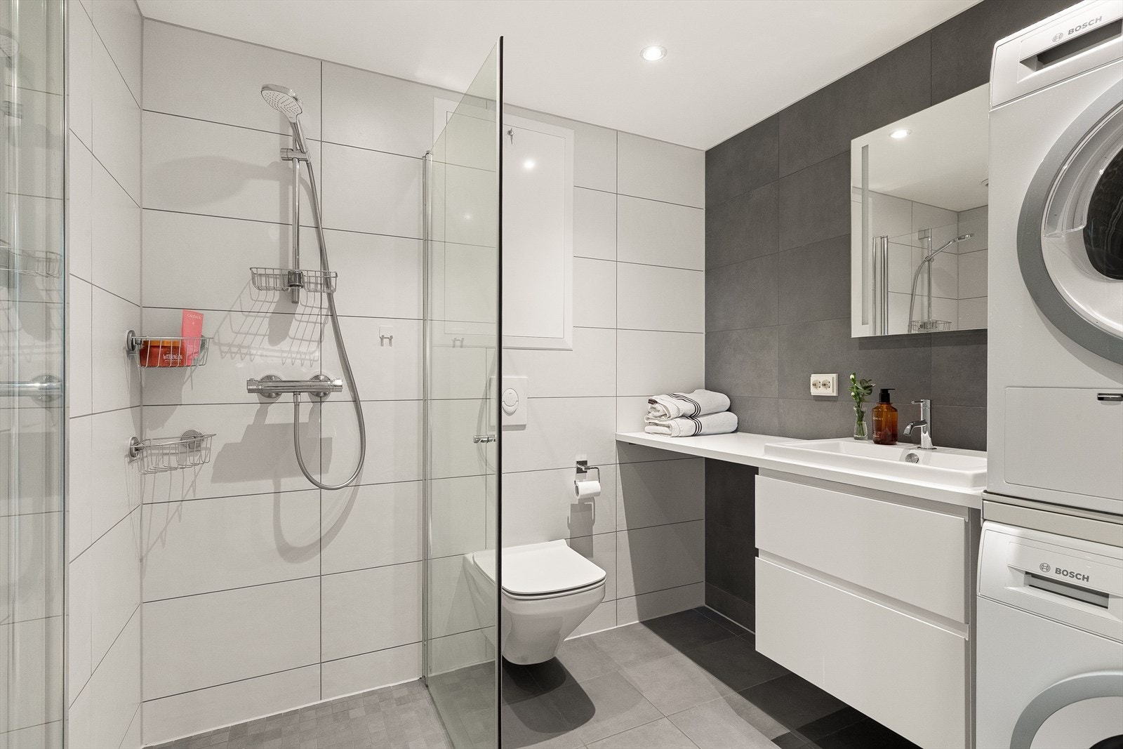 Leilighetens andre baderom er også et lyst og moderne flislagt baderom fra byggeår 2019. Baderommet har lysegrå fliser på gulv med vannbåren gulvvarme, store fine fliser på veggene og downlights i himlingen. Galleribilde