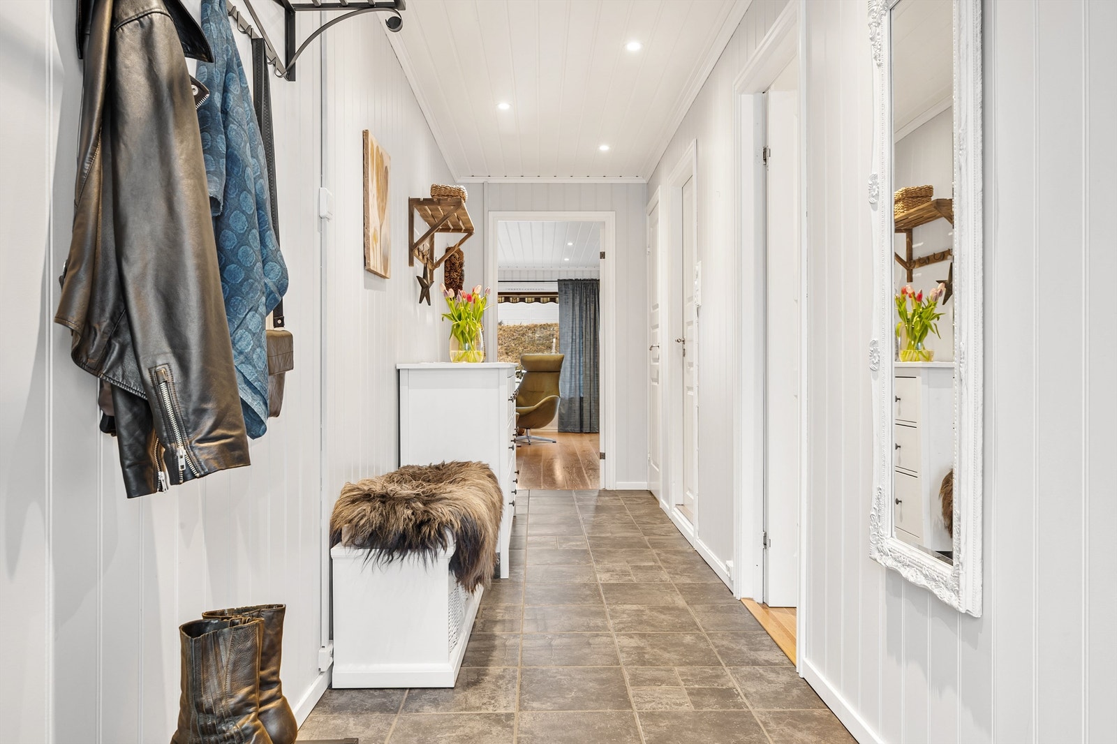 Entréen er flislagt med gulvvarme og har gode oppbevaringsmuligheter til ytterklær og lignende Galleribilde