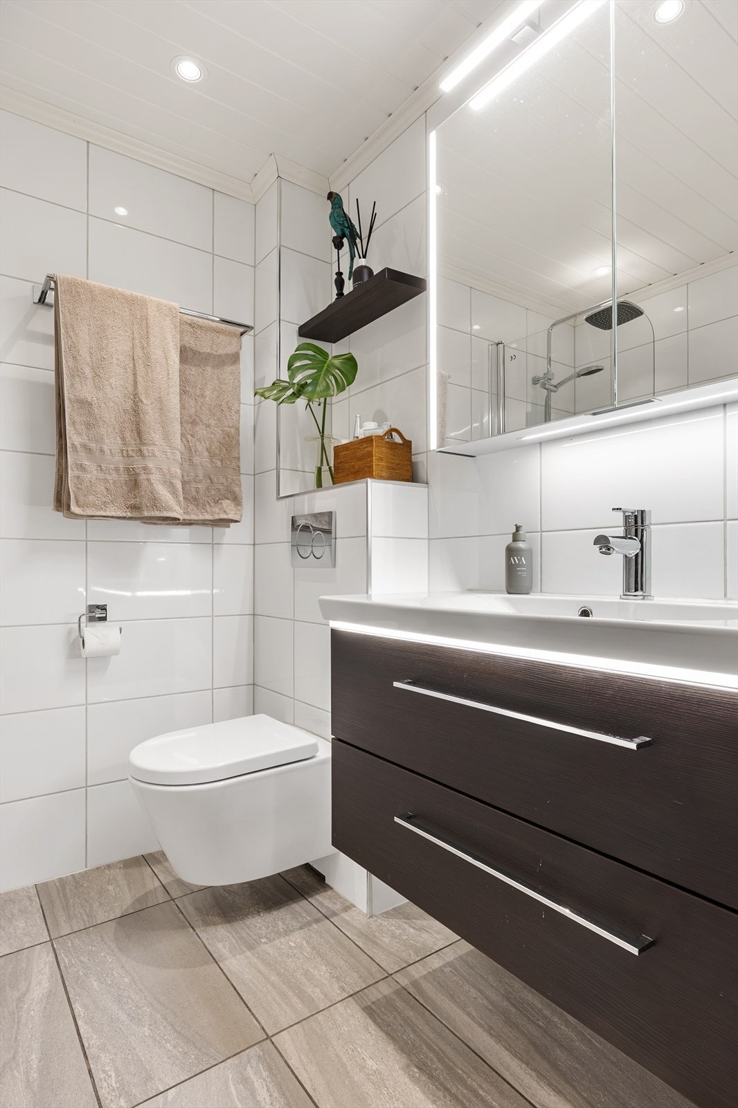 Badet har både vegghengt klosett og servant, med belysning i speildekket overskap Galleribilde