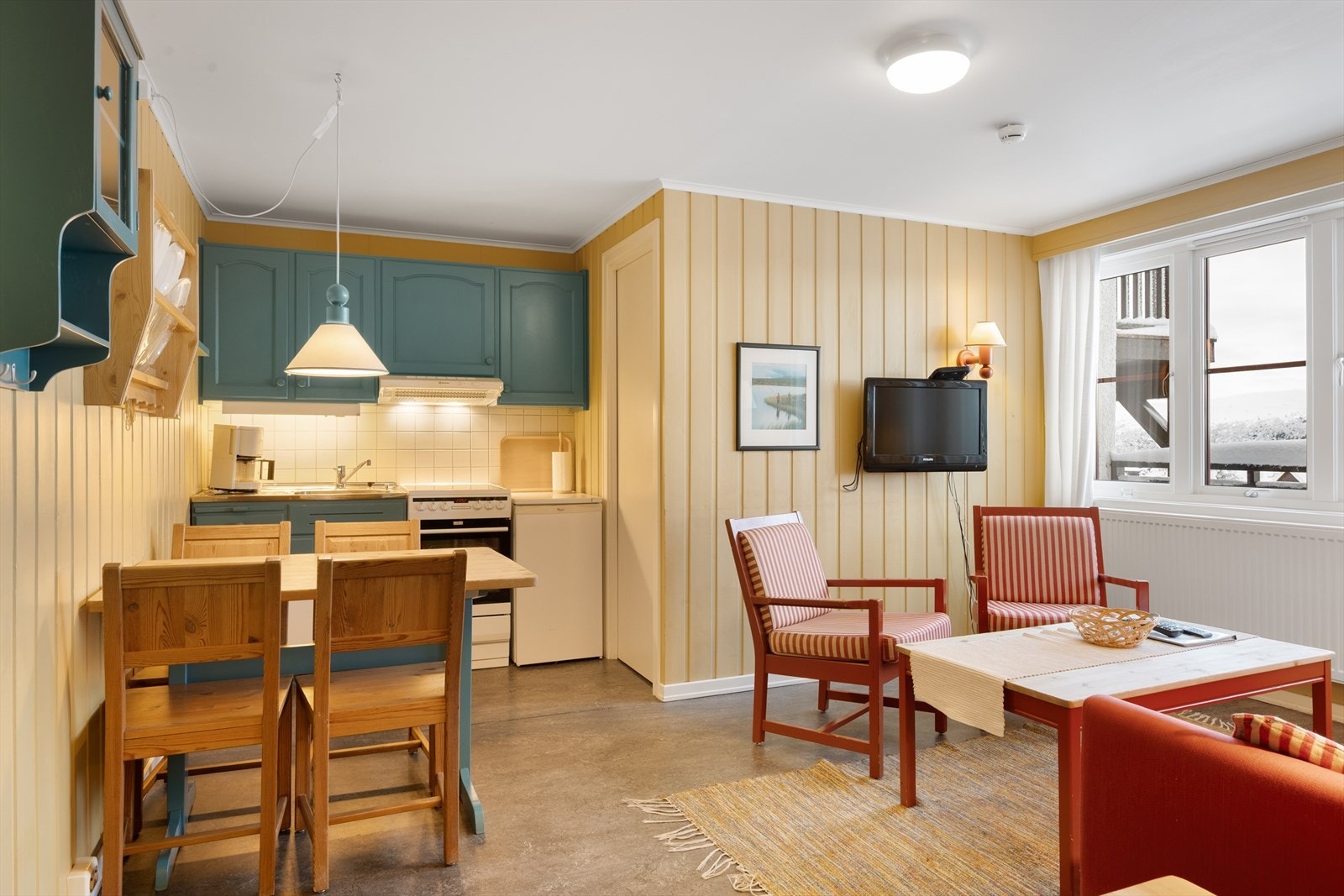 Den malte innredningen har profilerte fronter og stålkum - i tillegg plass til en hyggelig spiseplass. Galleribilde