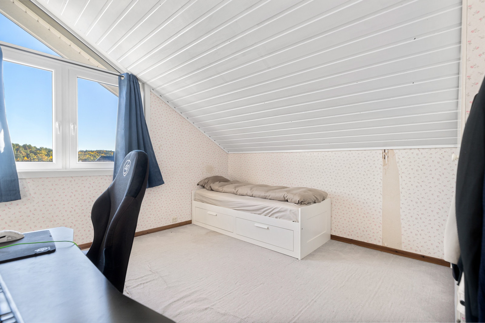 Soverom med seng og skrivepult, lyst og nøytralt innredet. Galleribilde